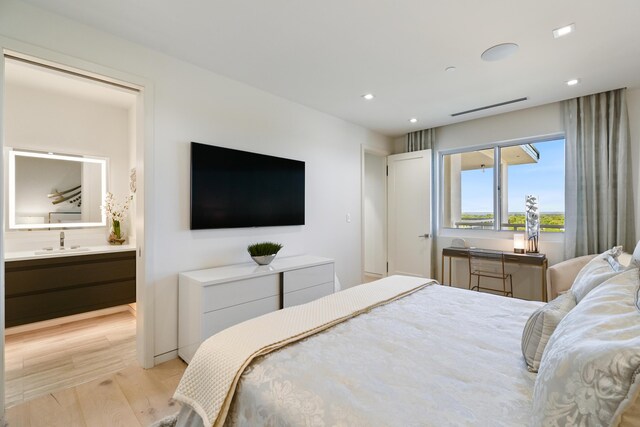 bedroom with sink, light hardwood / wood-style flooring, and ensuite bath