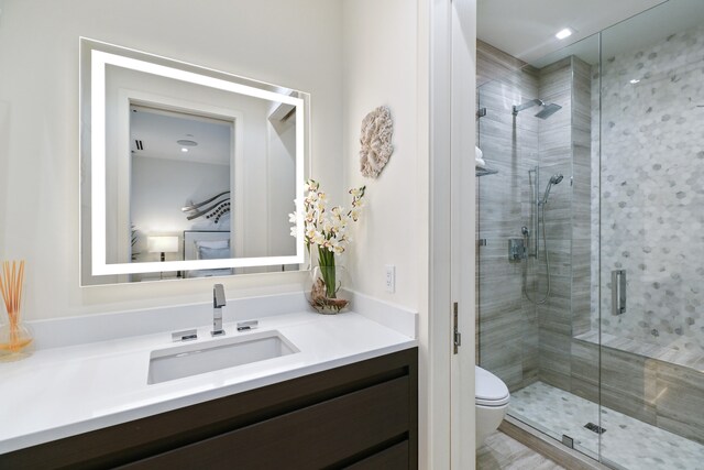 bathroom with vanity, toilet, and a shower with door