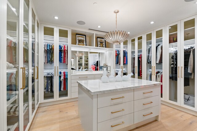 spacious closet featuring a notable chandelier and light hardwood / wood-style floors