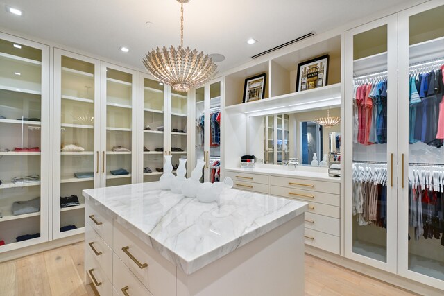 spacious closet featuring a notable chandelier and light wood-type flooring