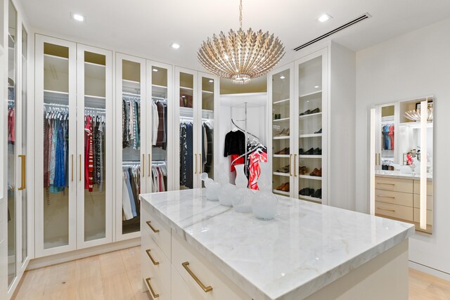 spacious closet featuring an inviting chandelier and light hardwood / wood-style floors