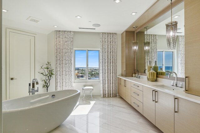 bathroom with a tub to relax in, vanity, and tile patterned floors