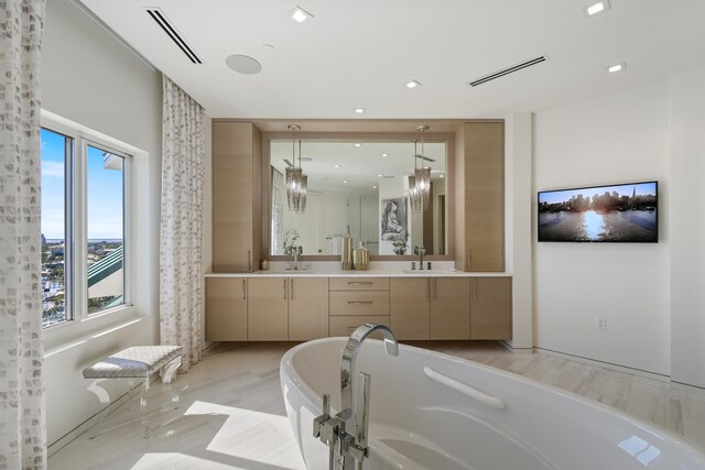 bathroom featuring a notable chandelier, hardwood / wood-style flooring, vanity, and a wealth of natural light