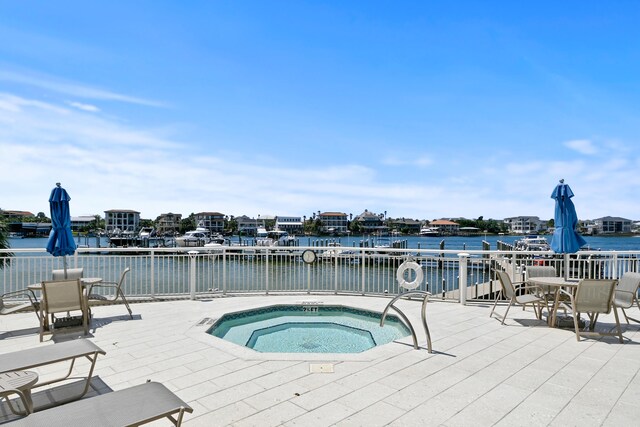 view of swimming pool with a patio, a water view, and a hot tub