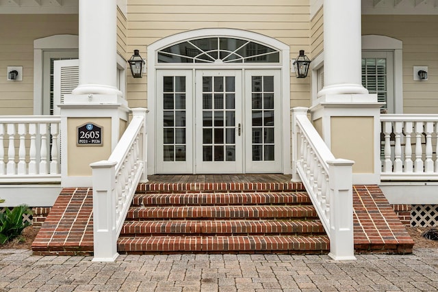 view of exterior entry with a porch and french doors