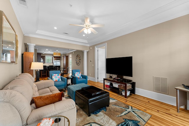 living room with ceiling fan, light hardwood / wood-style flooring, crown molding, and decorative columns