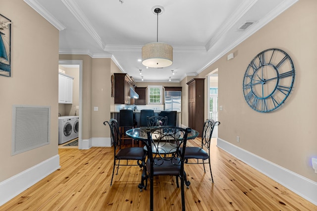 dining room featuring washer and clothes dryer, light hardwood / wood-style floors, and ornamental molding