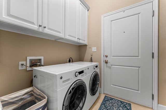 laundry room with washing machine and dryer, light tile patterned floors, and cabinets