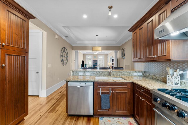 kitchen featuring sink, ventilation hood, kitchen peninsula, light hardwood / wood-style flooring, and appliances with stainless steel finishes