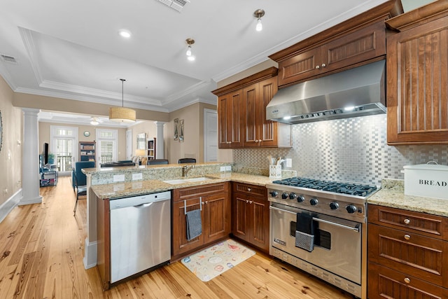 kitchen featuring light hardwood / wood-style floors, kitchen peninsula, appliances with stainless steel finishes, and ornate columns