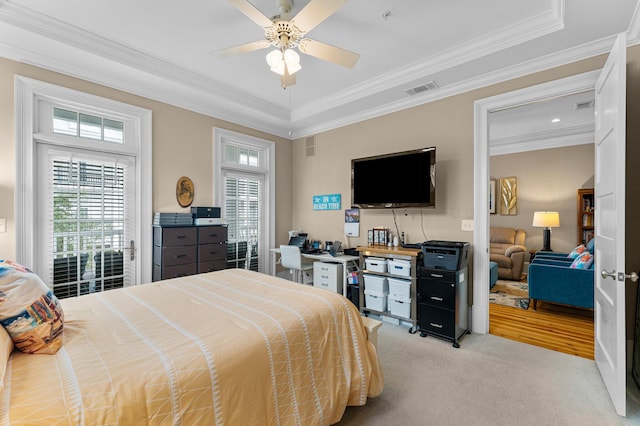 carpeted bedroom with ceiling fan, a tray ceiling, and ornamental molding