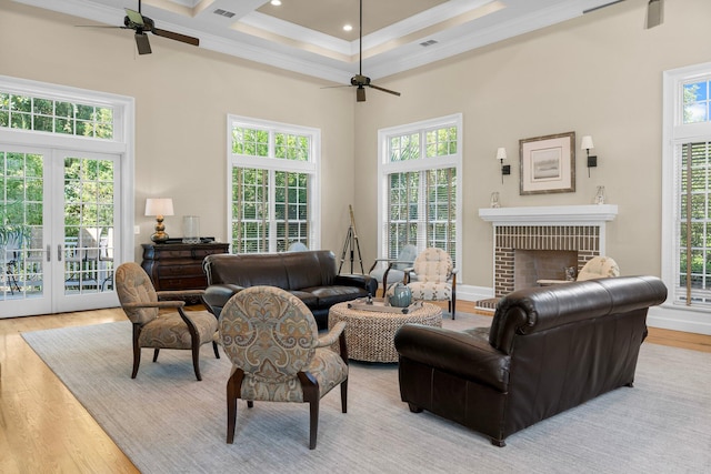 living room with a brick fireplace, light wood-type flooring, plenty of natural light, and a towering ceiling