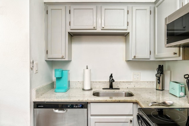 kitchen featuring appliances with stainless steel finishes, light stone countertops, sink, and white cabinets