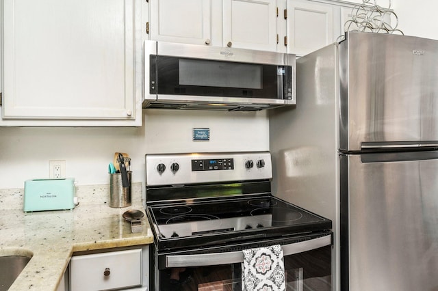 kitchen featuring stainless steel appliances, white cabinetry, and light stone counters