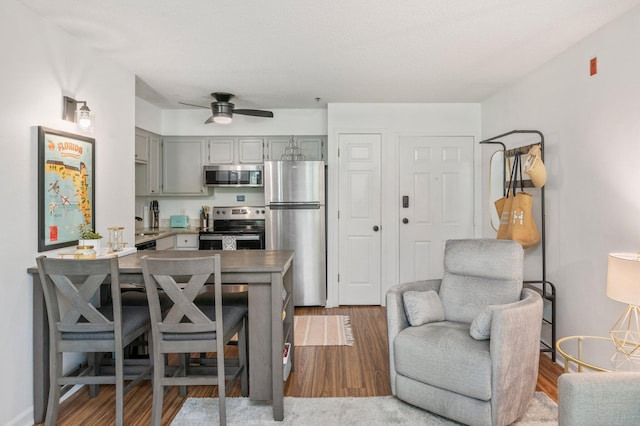 kitchen featuring ceiling fan, stainless steel appliances, dark wood-type flooring, and gray cabinetry