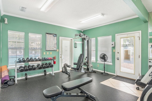 workout area featuring a textured ceiling, light tile patterned flooring, and ornamental molding