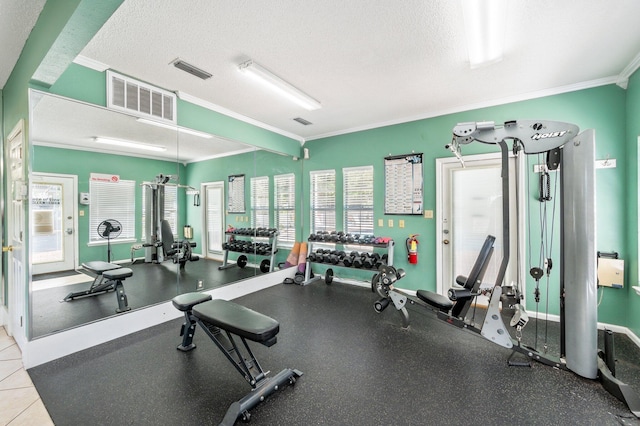 exercise room with a textured ceiling, crown molding, and light tile patterned floors