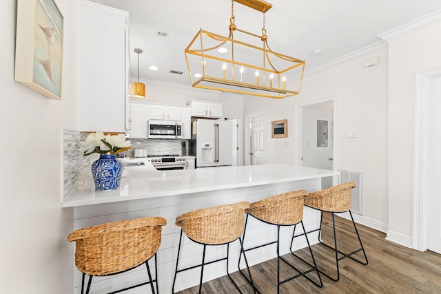 kitchen featuring appliances with stainless steel finishes, wood-type flooring, a kitchen bar, and white cabinets