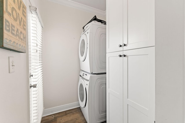 laundry area with cabinets, stacked washer and dryer, ornamental molding, and dark hardwood / wood-style flooring