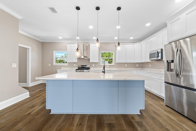 kitchen with wall chimney exhaust hood, a center island with sink, pendant lighting, stainless steel appliances, and white cabinets