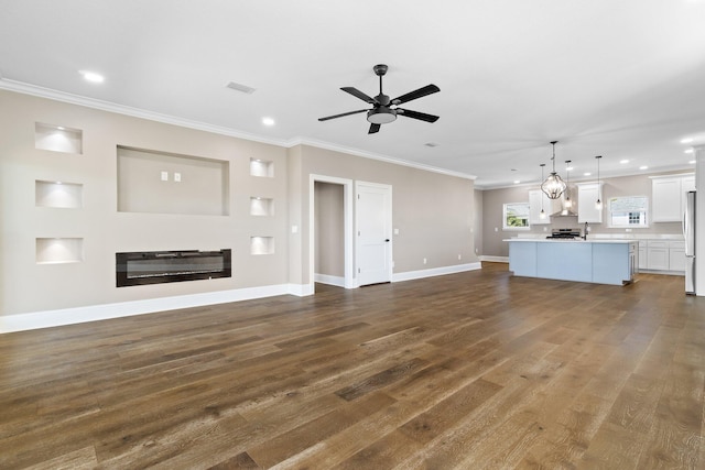 unfurnished living room featuring crown molding, ceiling fan, dark hardwood / wood-style flooring, and sink