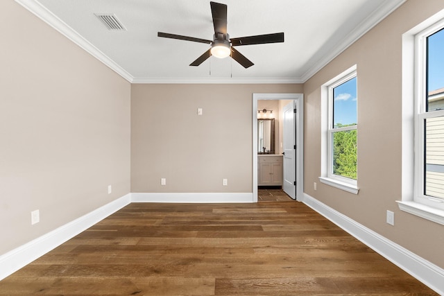 unfurnished bedroom featuring dark wood-type flooring, ensuite bath, ornamental molding, and ceiling fan