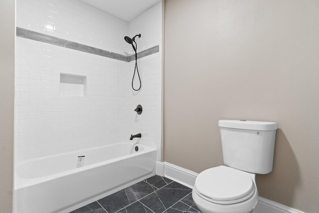 bathroom featuring tiled shower / bath, tile patterned floors, and toilet