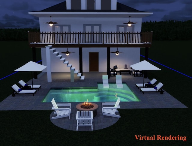 back of house at night featuring a patio area, an outdoor fire pit, a ceiling fan, stairs, and an outdoor pool