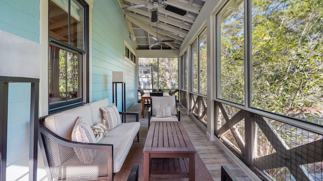 unfurnished sunroom featuring ceiling fan, vaulted ceiling with beams, and plenty of natural light