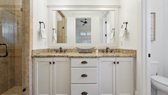 bathroom featuring ceiling fan, vanity, a shower with shower door, and toilet