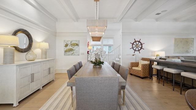 dining space featuring light wood-type flooring and beam ceiling