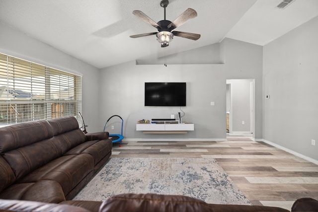 living room featuring ceiling fan, light hardwood / wood-style floors, and vaulted ceiling