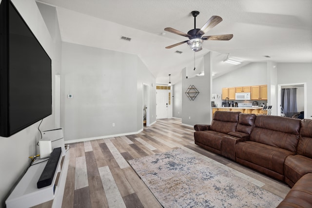 living room with ceiling fan, light wood-type flooring, and vaulted ceiling