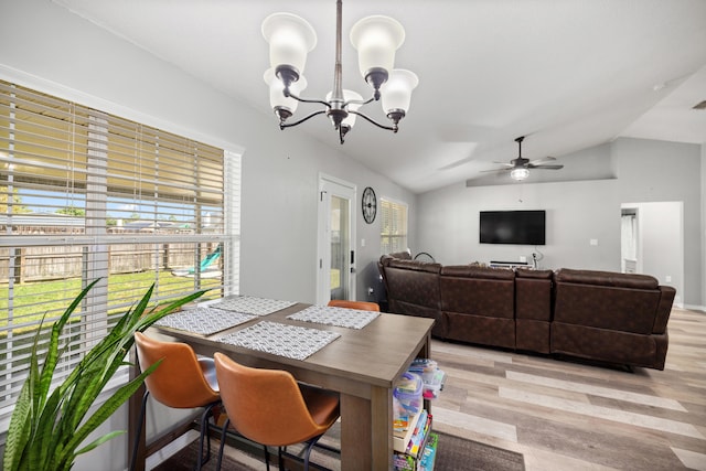 dining space with light hardwood / wood-style flooring, ceiling fan with notable chandelier, and vaulted ceiling