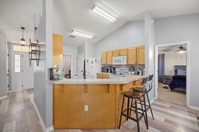 kitchen with lofted ceiling, white appliances, a kitchen breakfast bar, light hardwood / wood-style flooring, and kitchen peninsula