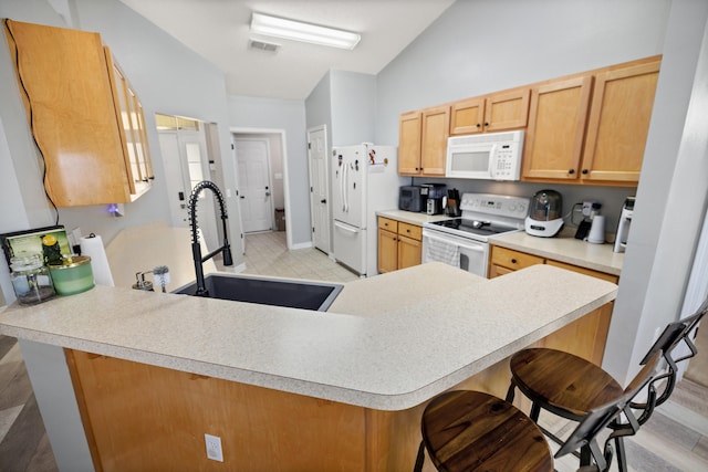 kitchen featuring vaulted ceiling, kitchen peninsula, sink, and white appliances