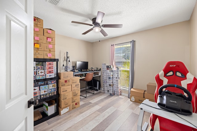 home office featuring a textured ceiling, light wood-type flooring, and ceiling fan