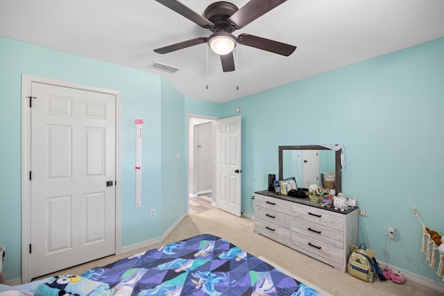 carpeted bedroom featuring ceiling fan and a textured ceiling