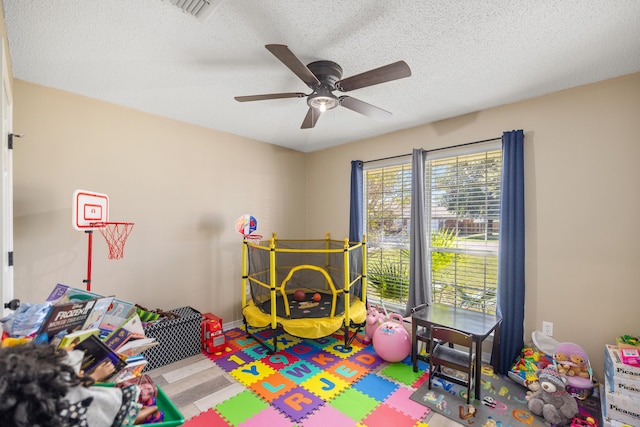 rec room with a textured ceiling and ceiling fan