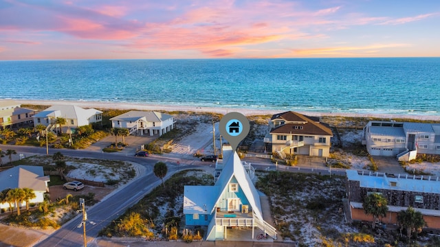 aerial view at dusk featuring a view of the beach and a water view