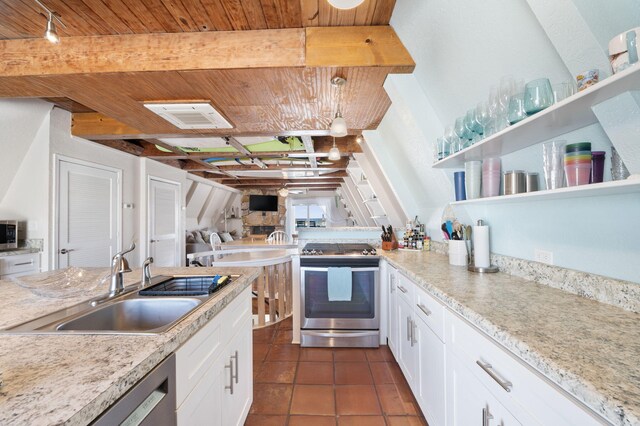 kitchen with dark tile patterned floors, sink, white cabinetry, stainless steel appliances, and light stone countertops