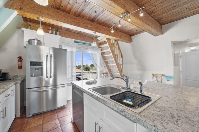 kitchen featuring pendant lighting, beamed ceiling, sink, white cabinetry, and appliances with stainless steel finishes