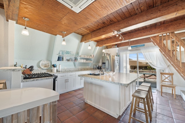 kitchen featuring white cabinets, hanging light fixtures, beam ceiling, a center island with sink, and stainless steel fridge with ice dispenser