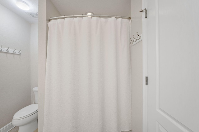 bathroom featuring toilet and a shower with shower curtain