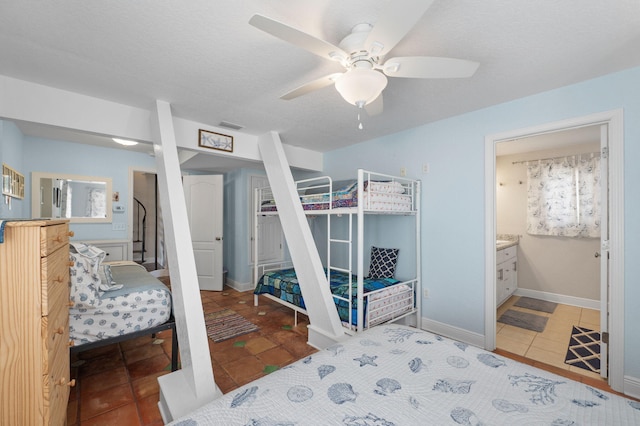 bedroom featuring ceiling fan, a textured ceiling, tile patterned flooring, and ensuite bathroom