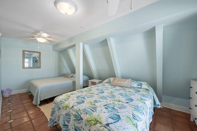 tiled bedroom with ceiling fan and a textured ceiling