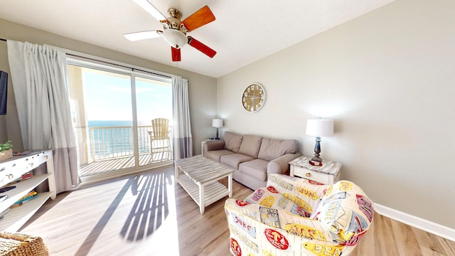 living room with ceiling fan, light wood-type flooring, vaulted ceiling, and a water view