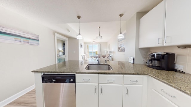 kitchen featuring decorative light fixtures, stainless steel dishwasher, sink, and white cabinets