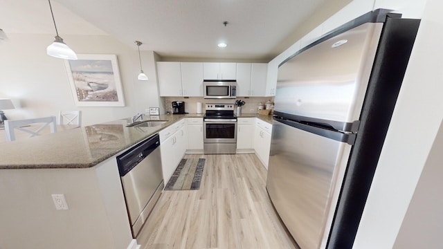 kitchen with sink, white cabinetry, kitchen peninsula, appliances with stainless steel finishes, and decorative light fixtures