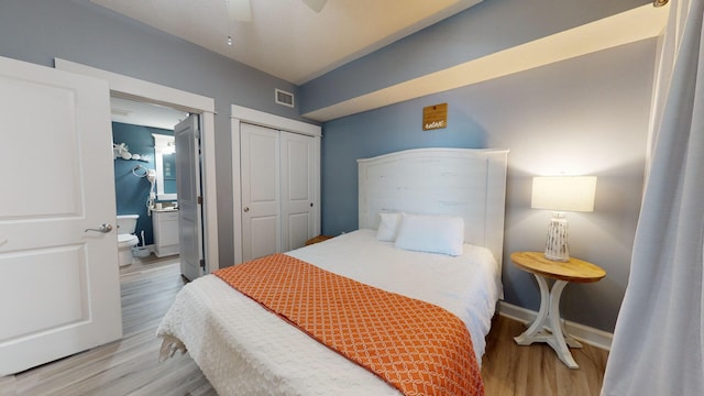 bedroom with a closet, light hardwood / wood-style floors, ceiling fan, and connected bathroom